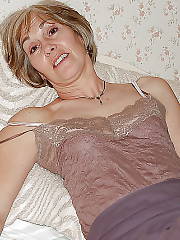 Sexy blonde MILF on bed pleasuring herself.